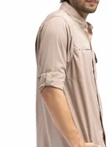 Camisa negra de manga larga con dos bolsillos frontales con tapa y velcro. Tiene la opción de arremangado con presilla y botón para mantenerla fija. Cuenta con una abertura posterior que favorece la ventilación.