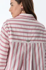Camisa blanca con rayas verticales rojas, de corte holgado, manga larga y bolsillo en el pecho.