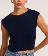 Blusa corta de punto color crema, con cuello redondo y hombros caídos.