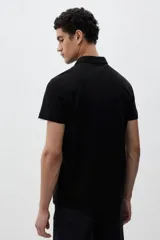 Chomba negra de piqué de algodón, corte slim fit, con cuello clásico, tapeta de dos botones y mangas cortas.