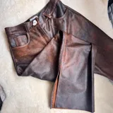 Pantalón de cuero negro, de corte recto y tiro alto, con bolsillos delanteros y traseros.