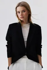 Blazer negro de lino y viscosa con solapas de pico, hombreras finas y cierre de un botón. Modelo entallado con pinzas en la cintura, abertura con botón en los puños y bolsillos delanteros ribeteados. Abertura atrás y forro interno.