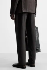 Pantalón de vestir negro de corte recto, confeccionado en tejido de algodón con acabado ligeramente encerado. Cuenta con bolsillos laterales y traseros de vivo. El cierre frontal es con cremallera y gancho metálico oculto.