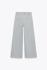 Pantalón de jean celeste de tiro alto y corte wide leg, con bolsillos frontales y traseros, cierre frontal con cremallera y botón metálico.