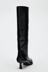 Bota de caña alta color negro de cuero sintético, con punta fina y tacón kitten.