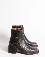 Bota corta de cuero charol negro, con caña baja, cierre lateral y taco cuadrado de madera.