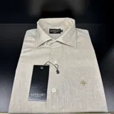 Camisa de hombre de lino color beige jaspeado, de la marca Ganbaru Collection. Tiene cuello clásico, cierre con botones y logo bordado en el pecho.