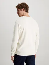 Sweater de punto color crema, de corte recto, con cuello redondo y logo de Calvin Klein en el pecho.
