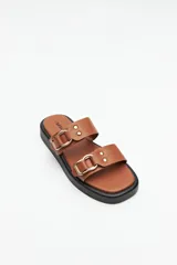 Sandalias marrones con plataforma baja y tiras anchas con hebillas metálicas.