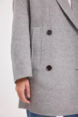 Tapado gris de lana con doble botonadura, cuello con solapas y bolsillos laterales.