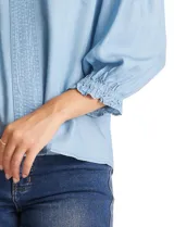 Blusa de lyocell color azul claro, con escote en V, detalles de costuras verticales en el frente y mangas tres cuartos con puños elastizados.