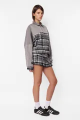 Minifalda gris con estampado de cuadros escoceses, cintura ancha, tablas en la parte inferior y cierre metálico lateral. Incluye sobrefalda desmontable con bolsillo.