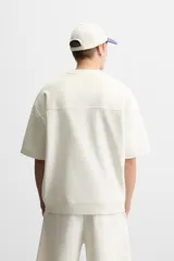 Sudadera negra de corte relaxed fit, confeccionada en tejido interlock de algodón con elasticidad. Tiene cuello redondo, manga corta y bajo acabado en rib.