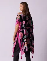 Kimono tejido con estampado floral multicolor, terminación de ruedo con borlas y mangas cortas con borde celeste.