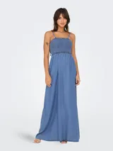 Vestido largo de lyocell color azul denim, con breteles finos con lazos, cuerpo elastizado y falda amplia con tajo lateral.