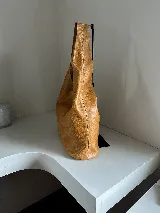 Maxi cartera tipo bolso de cuero natural, con base plana y diseño simple sin metales.