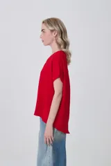 Blusa holgada de poliéster color blanco, con escote en V profundo y pinzas frontales que generan caída. Mangas cortas.