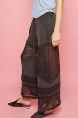 Pantalón negro de corte relajado con cintura elástica y detalles de red en los laterales y en el ruedo.