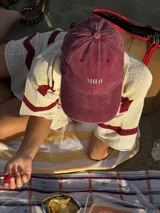 Gorra de gabardina color borgoña con visera curva y bordado frontal con la palabra "MILO" en letras blancas.