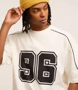 Remera de corte boxy color crema con estampa del número 96 en el frente y detalles en negro en cuello y mangas.