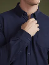 Camisa de piqué color blanco, con un bolso en el pecho y botones frontales.