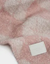Bufanda tejida color rosa y beige con estampado de rombos y terminación de flecos.