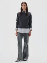 Jean de mujer, tiro medio, corte flare (campana) con estampado de rayas verticales en tonos gris oscuro y verde grisáceo. Confeccionado en denim 100% algodón.