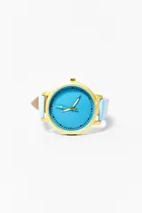 Reloj de pulsera con caja dorada, esfera celeste con indicadores de hora en forma de puntos y agujas doradas. La correa es de cuero celeste.