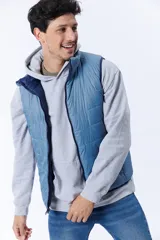 Chaleco acolchado azul marino con cierre frontal y cuello alto. Reversible, con interior en tono celeste. Sin mangas.