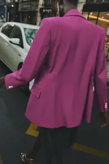 Blazer negra entallada con cuello solapa, manga larga con hombreras, bolsillos delanteros con solapa y cierre frontal con botones dorados.