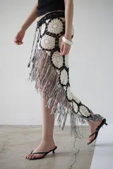 Falda larga de crochet color crudo y negro, con diseño de flores y flecos en el ruedo.