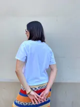 Remera blanca de algodón con estampado frontal de un bodegón en color rojo y la inscripción "Sanguchito Club. Lo simple, lo fresco de la vida".