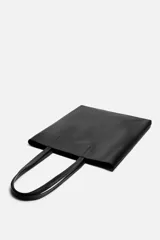 Bolso tipo shopper fabricado en cuero color negro. Tiene un bolsillo interior plano con cierre mediante cremallera y asas de cuero.