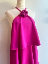 Minivestido negro con escote halter con detalle de flor, corte escalonado y falda corta.