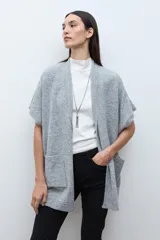 Ruana de tejido de punto color rosa melange, sin mangas y con cuello redondo.