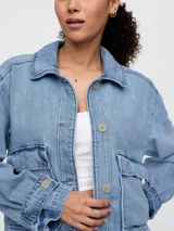 Campera de jean celeste, corte recto, con cuello clásico, cierre frontal con botones, mangas largas con puños abotonados, bolsillos de parche con solapa en el pecho y bolsillos laterales.