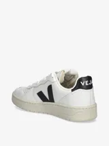 Zapatillas deportivas Veja modelo V-10, color blanco con logo lateral en negro y detalle en el talón en negro. Fabricadas en cuero natural con suela de goma. Producto elaborado parcialmente con caucho natural de la selva amazónica.