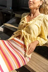 Camisa amarilla con bordado inglés, escote en V, mangas largas abullonadas con puños elásticos y lazos decorativos en el frente.