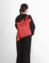 Mochila acolchada color ladrillo con cierre superior enrollable, correas ajustables y logo estampado en blanco.