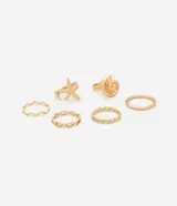 Set de seis anillos dorados de metal reciclado, con diseños delicados y motivos marinos como una espiral y una estrella de mar.