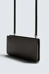 Bandolera rectangular color marrón oscuro con textura grabada. Tiene un compartimento principal con cierre de cremallera, seis ranuras para tarjetas, una ranura para billetes, monedero con cremallera, bolsillo trasero con botón a presión y asa de hombro ajustable y extraíble.