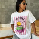 Remera blanca de manga corta con estampa de un trago de verano con rayas verticales rosas de fondo.