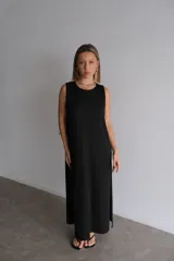 Vestido largo azul marino de tejido acanalado, con escote redondo y mangas cortas tipo hombrera. Presenta una abertura lateral en la falda.