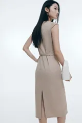 Vestido midi color beige de punto pesado con escote bote y manga japonesa. Modelo de corte entallado con costura vertical decorativa en delantero y espalda, y cinturón fino extraíble. Abertura atrás.