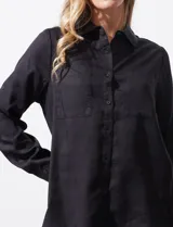 Camisa blanca de lyocell, marca Cyrus. Tiene cuello con solapa, abertura central con botones, mangas largas regulables con presilla y botón, y dos bolsillos delanteros aplicados.
