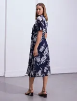Vestido largo de gasa estampada con flores blancas sobre fondo azul marino, marca Sandra Darren. Tiene escote en V cruzado, cintura elastizada con lazo de ajuste, falda plisada y forro interno a tono.