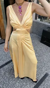 Vestido largo color durazno con escote pronunciado en V y aberturas laterales en la cintura. Presenta un drapeado frontal y falda con tajo lateral.