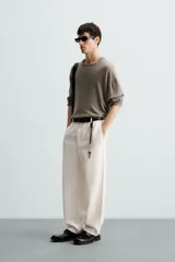 Pantalón de vestir color blanco hueso, de corte recto y tiro medio, con cintura elástica y cierre frontal de botón y cremallera. Presenta bolsillos frontales y bolsillos traseros de vivo.