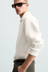Sweater color crema de punto con cuello polo y escote en V.