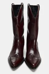 Bota de cuero color borgoña, estilo cowboy, con puntera fina y tiradores laterales.